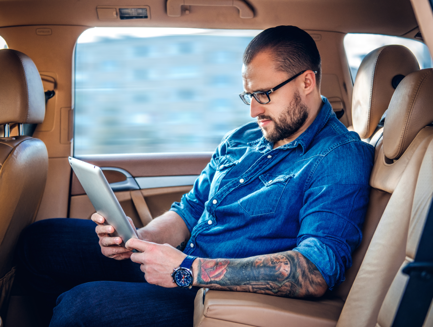 stylish-bearded-male-eyeglasses-with-tattoo-his-arm-using-portable-tablet-pc-back-seat-car